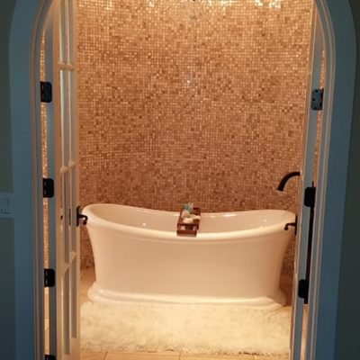 Tiled bathroom with chandelier and raised bathtub