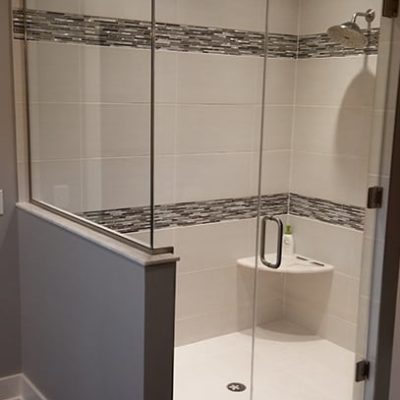 Glass encased shower with white and grey tile