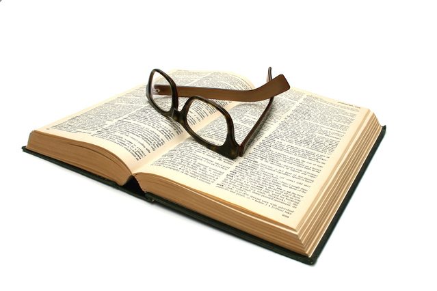 close up photo of book with reading glasses